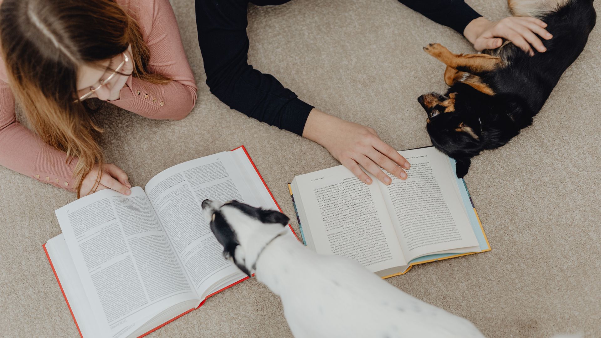 Dog's and people lying on the floor with books open